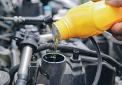 A man is pouring oil into a car engine