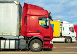 Colorful modern big semi-trucks and trailers of different makes and models stand in row on flat