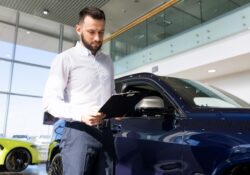 the seller at the car dealership prepares documents for the buyer of the car