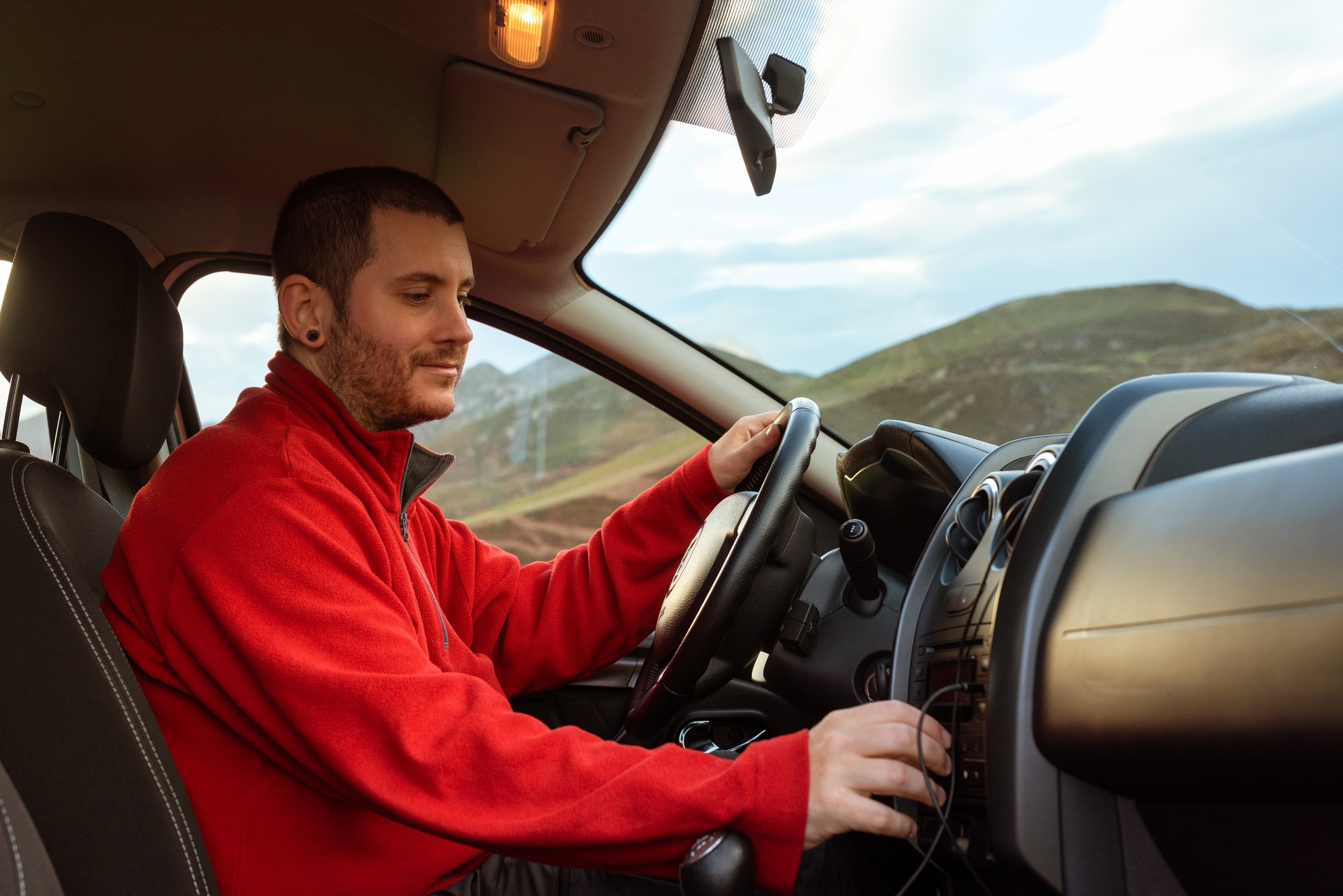 young man tuning into his car radio