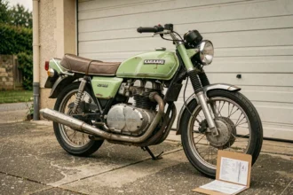 Kawasaki KZ 400 ancienne des années 70 garée devant un garage avec un dossier d'assurance posé contre la roue arrière