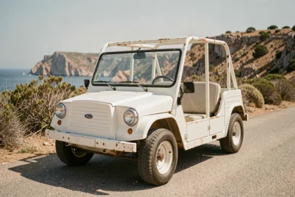 Mini Moke vintage garée sur une route côtière méditerranéenne, vue trois quarts avant mettant en valeur la carrosserie patinée et l'habitacle ouvert, idéale pour illustrer un article d'achat de Mini Cooper Moke en 2026